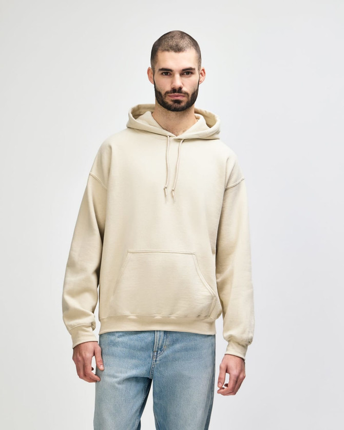 A beige hooded sweatshirt with a front pocket and drawstrings, worn by a model. It features a logo.