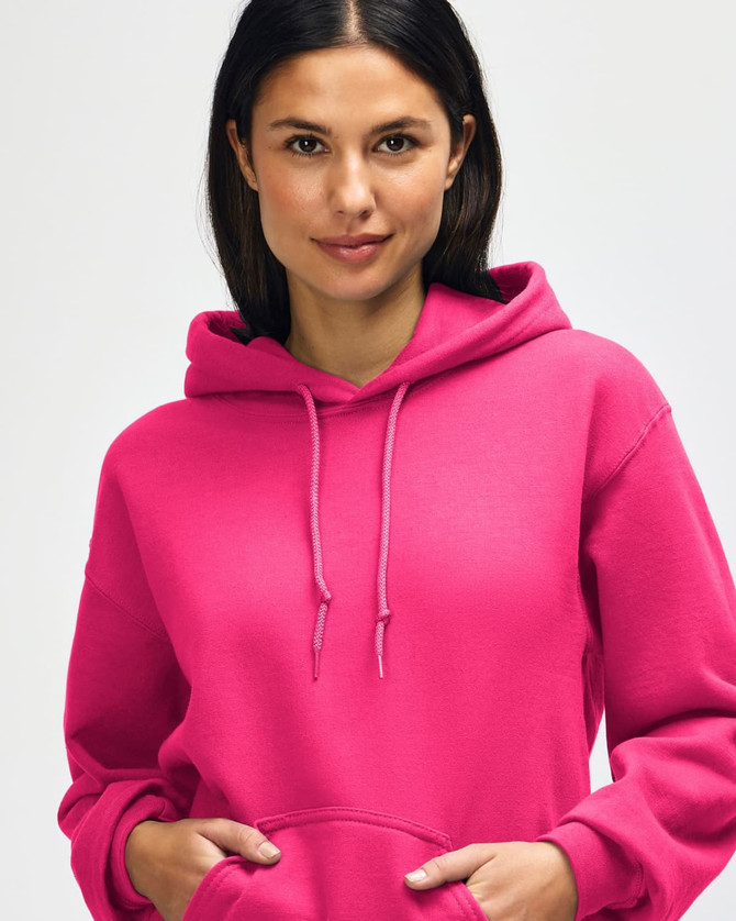 A bright pink hooded sweatshirt featuring a front pocket and drawstrings, worn by a model adjusting the hood.