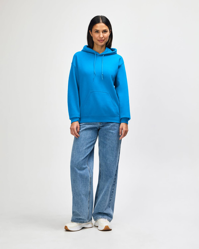 A woman in a bright blue hooded sweatshirt and jeans stands with her hands in the pockets.