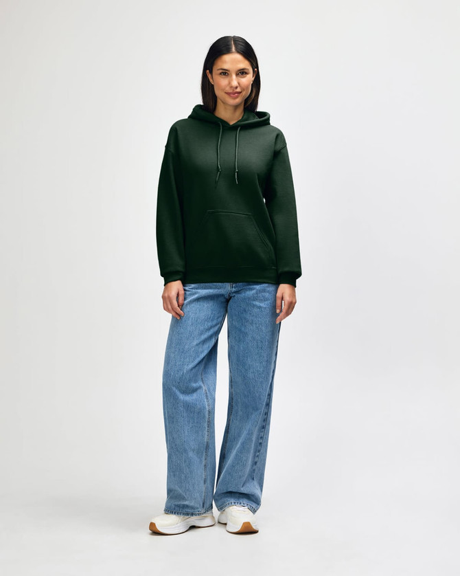A woman wearing a green hooded sweatshirt with a kangaroo pocket, paired with blue jeans and white sneakers.