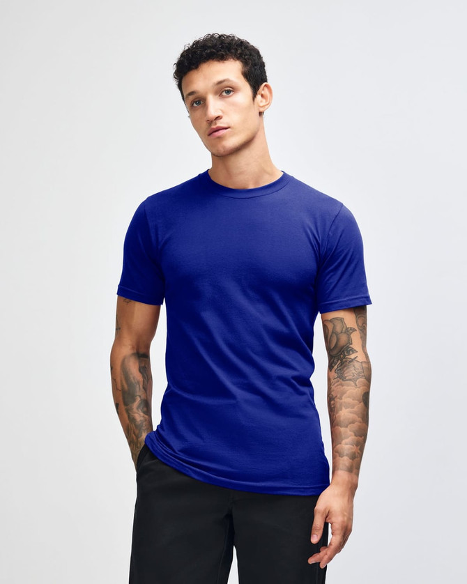 A blue unisex short sleeve t-shirt displayed on a model with curly hair. Features a logo on the shirt.
