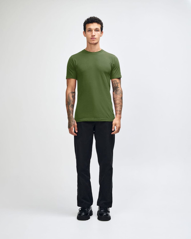 A green unisex short sleeve t-shirt worn by a model, paired with blue jeans and black shoes. Branding visible.
