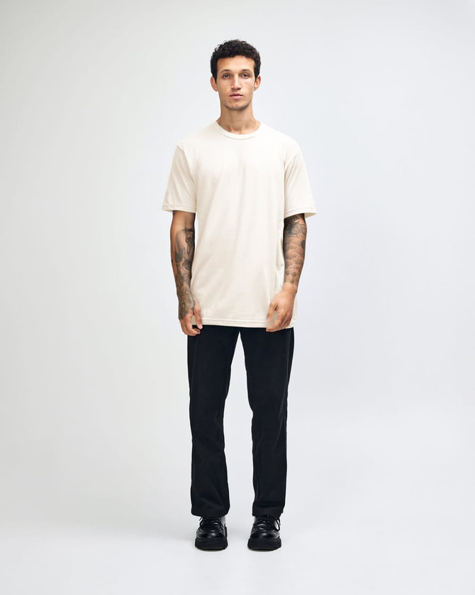 A unisex fine jersey short sleeve t-shirt in a light yellow colour, worn by a model. It has a logo.