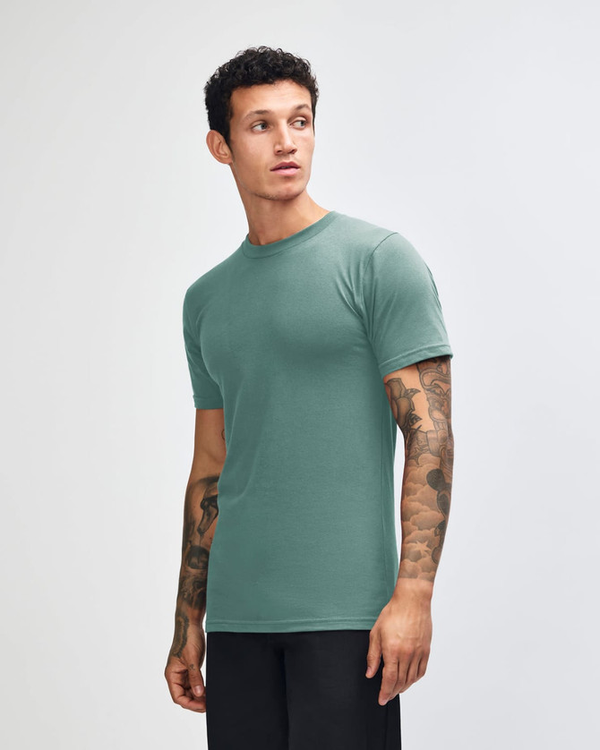 A unisex short sleeve T-shirt in teal, featuring a logo on the front, displayed from the side.