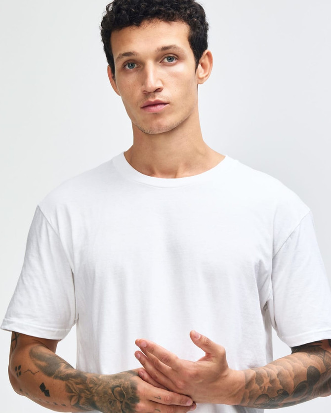 A white unisex short sleeve t-shirt displayed on a model paired with black leggings and white sneakers.