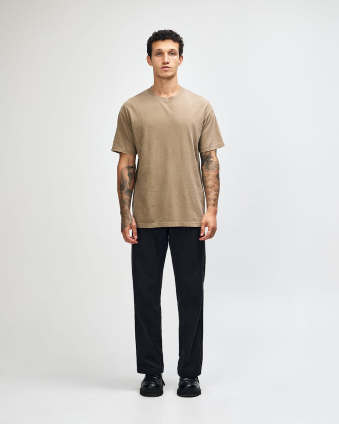A unisex heavyweight cotton T-shirt in earthy brown, worn with light blue jeans and dark sneakers.