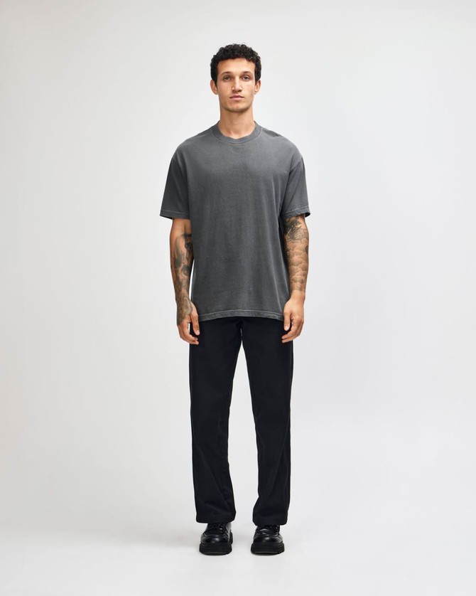 A model wearing a grey heavyweight cotton t-shirt paired with olive green cargo pants. The shirt has a logo.