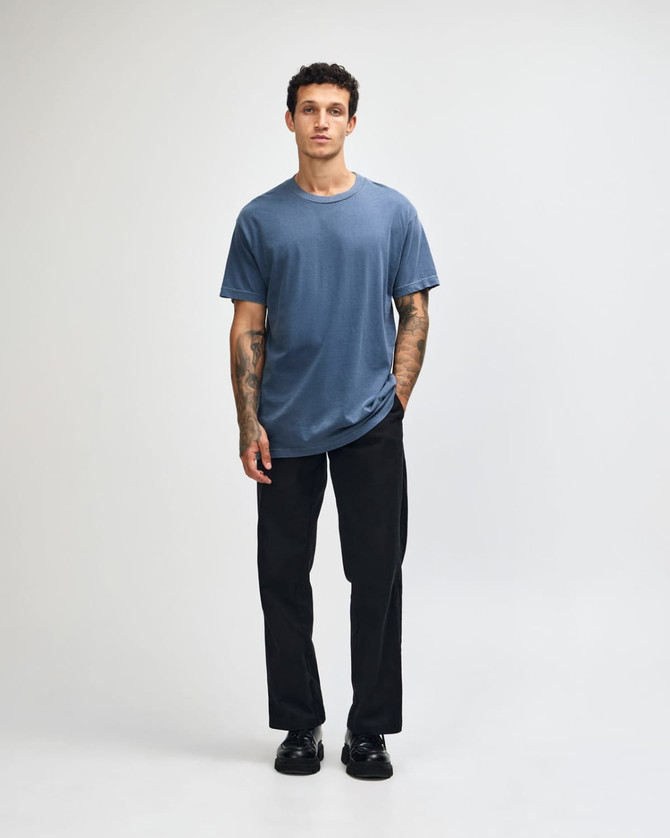 A navy unisex t-shirt made of heavyweight cotton, modelled by a person wearing light cargo jeans.