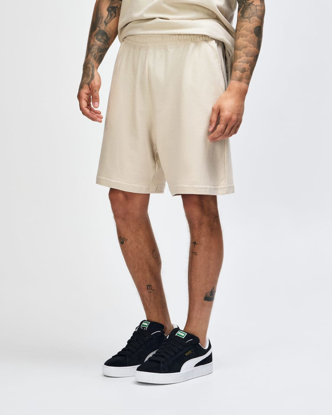 Beige unisex gym shorts with an elastic waistband and pockets, featuring a logo on the side.