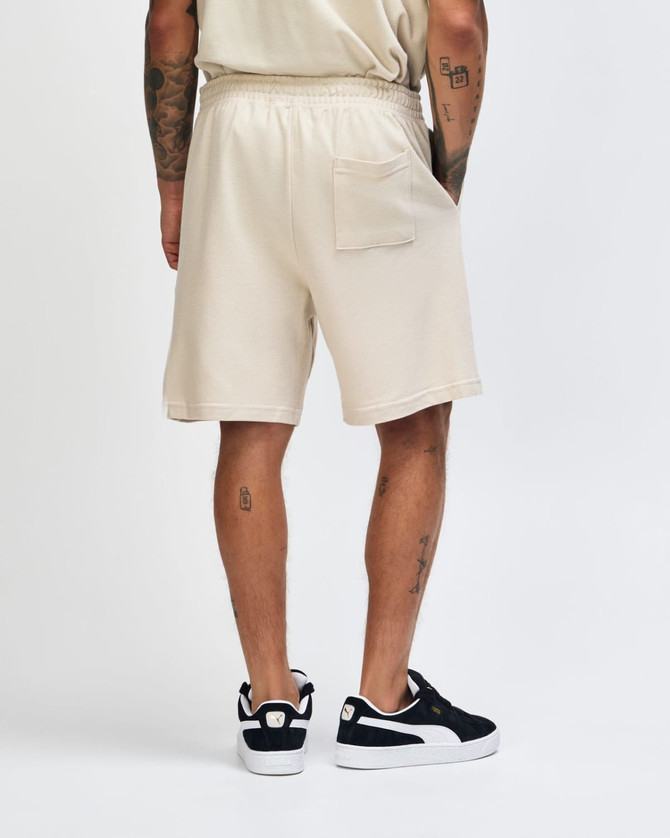Beige unisex pique gym shorts featuring an elastic waistband and a single back pocket.