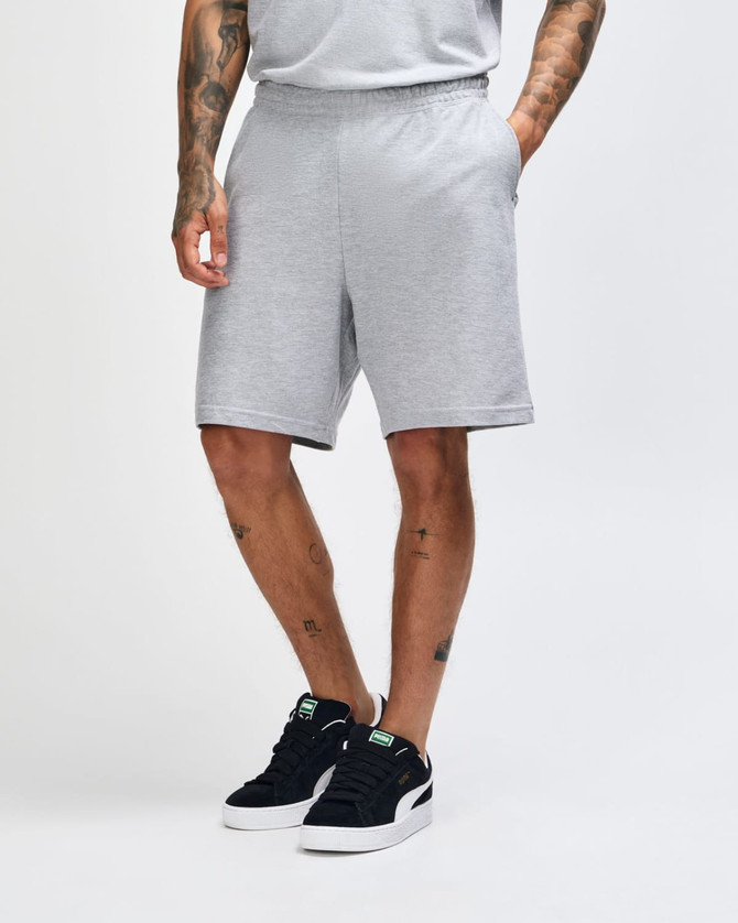 Light grey unisex gym shorts with an elastic waistband and side pockets, displayed on a model from the side.