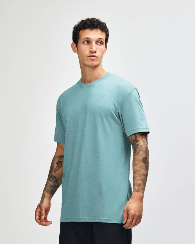 A teal unisex CVC short sleeve t-shirt displayed on a model, featuring a simple design and relaxed fit.