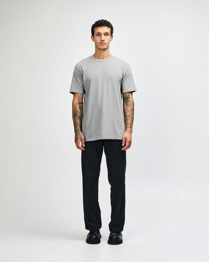 A grey unisex CVC short sleeve t-shirt worn with black cargo pants, featuring a simple design and casual fit.