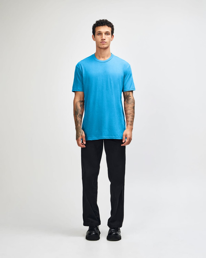 A unisex CVC short sleeve t-shirt in bright blue, worn with black cargo pants, featuring a casual style.