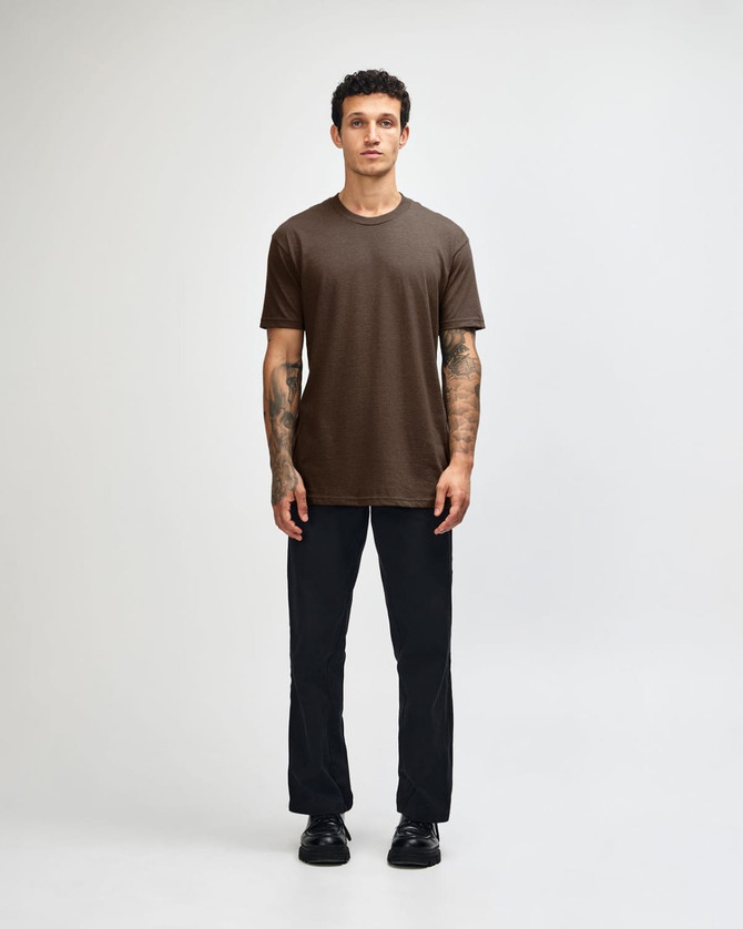 A unisex short sleeve T-shirt in brown, displayed by a model, paired with dark cargo pants and footwear.