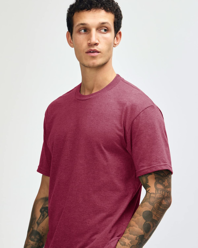 A maroon unisex CVC short sleeve T-shirt on a model with tattoos, featuring a logo on the shirt.