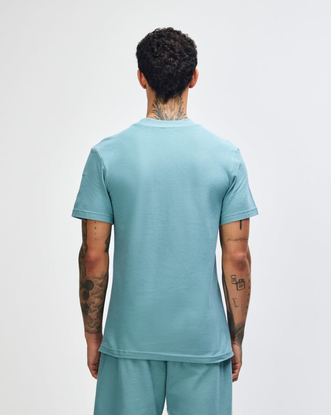A green mockneck unisex T-shirt featuring a back view of the garment. It has a logo.