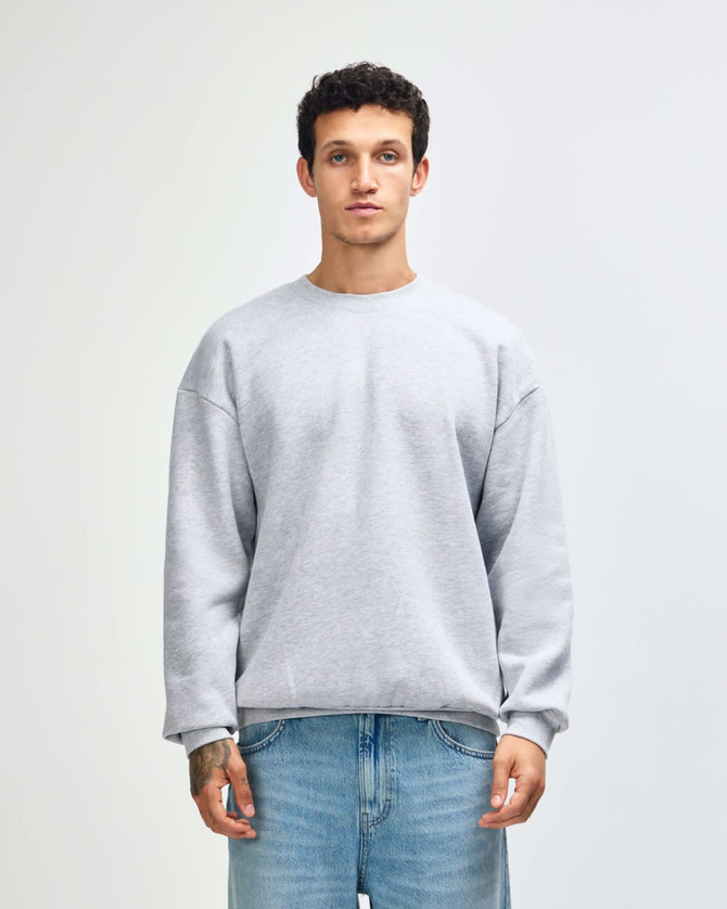 A unisex crewneck sweatshirt in light grey, featuring long sleeves and a comfortable fit. It has a branding logo.
