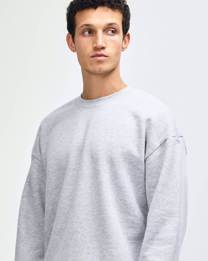 A unisex crewneck sweatshirt in grey, featuring long sleeves and a comfortable fit. It includes a logo.