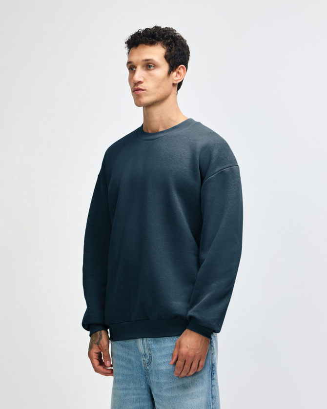 A unisex crewneck sweatshirt in teal, featuring a relaxed fit and a logo on the sleeve.