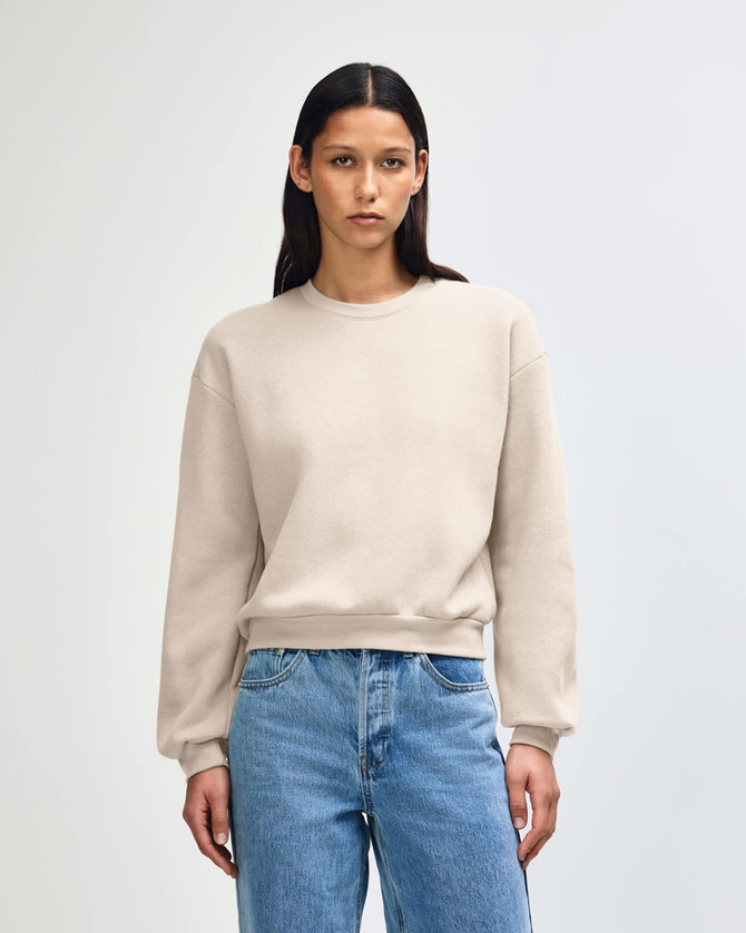 A women's crewneck sweatshirt in a beige colour, featuring a relaxed fit and long sleeves. It has a simple logo.