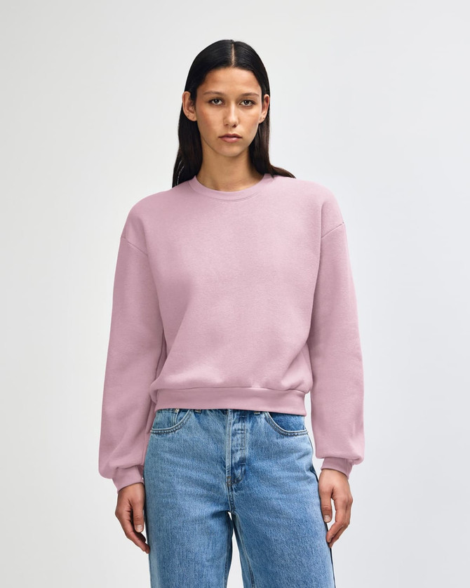 A women's crewneck sweatshirt in a soft pink colour, featuring a relaxed fit and long sleeves. It has a logo.