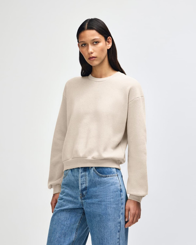 A cream women's crewneck sweatshirt with a relaxed fit, featuring long sleeves and a simple design.