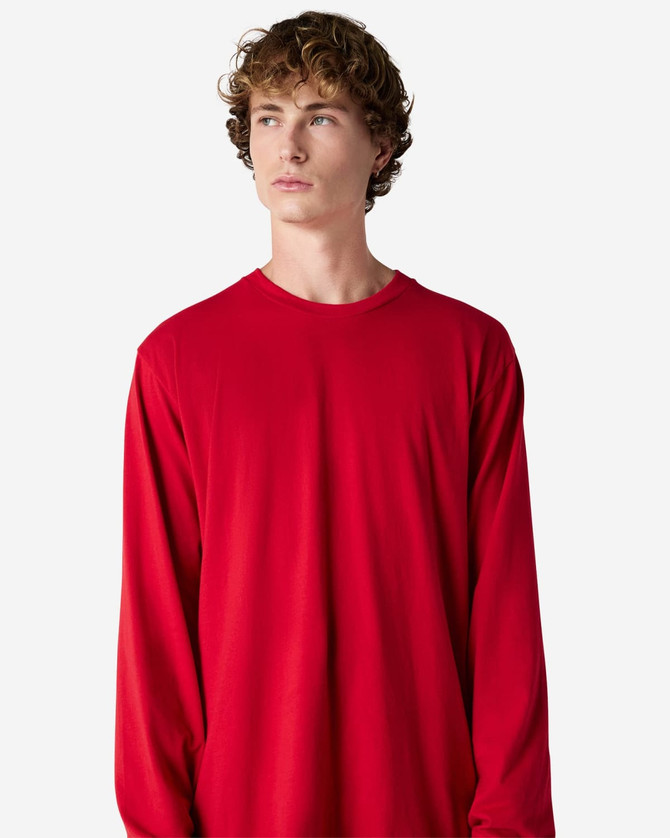 A model wearing a red long sleeve t-shirt, featuring a relaxed fit and crew neck. The shirt has a logo.