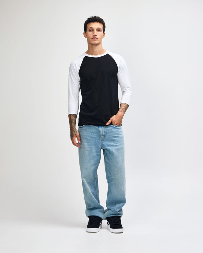 A unisex raglan T-shirt with a black body and white three-quarter sleeves, paired with light blue jeans and black sneakers.
