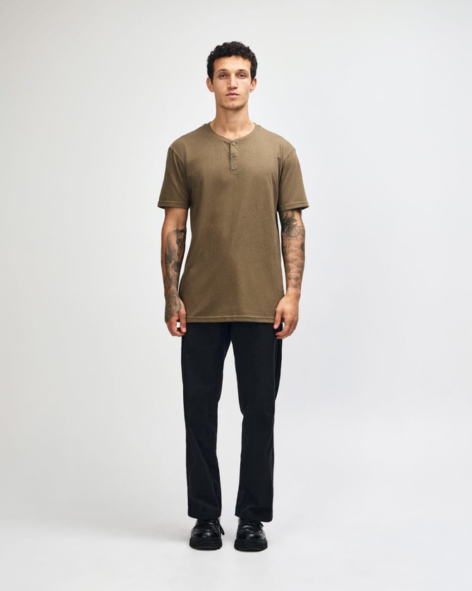 A unisex henley T-shirt in olive green, paired with light blue baggy jeans, displayed on a model.