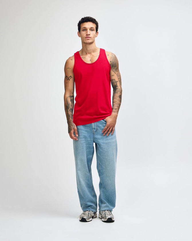 A red unisex fine jersey tank is worn by a model, paired with black cargo trousers and white sneakers.