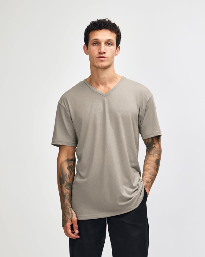 A unisex V-neck T-shirt in a muted beige colour with short sleeves and a relaxed fit. It features a logo on the garment.