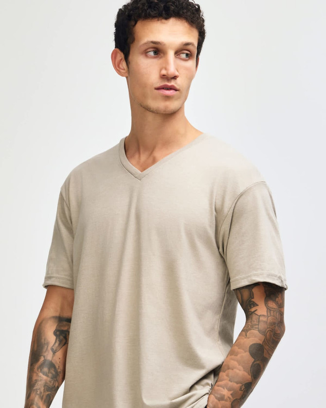 A unisex beige V-neck T-shirt with a relaxed fit, featuring a logo on the side.
