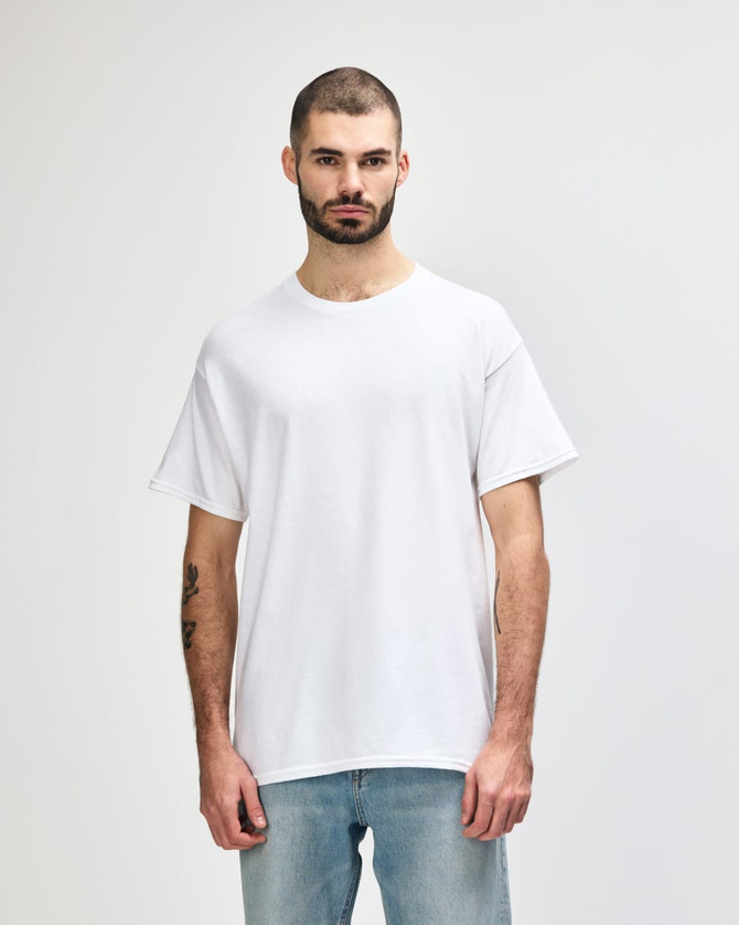 A plain white Gildan Heavy Cotton adult T-shirt on a model, featuring short sleeves and a round neckline.
