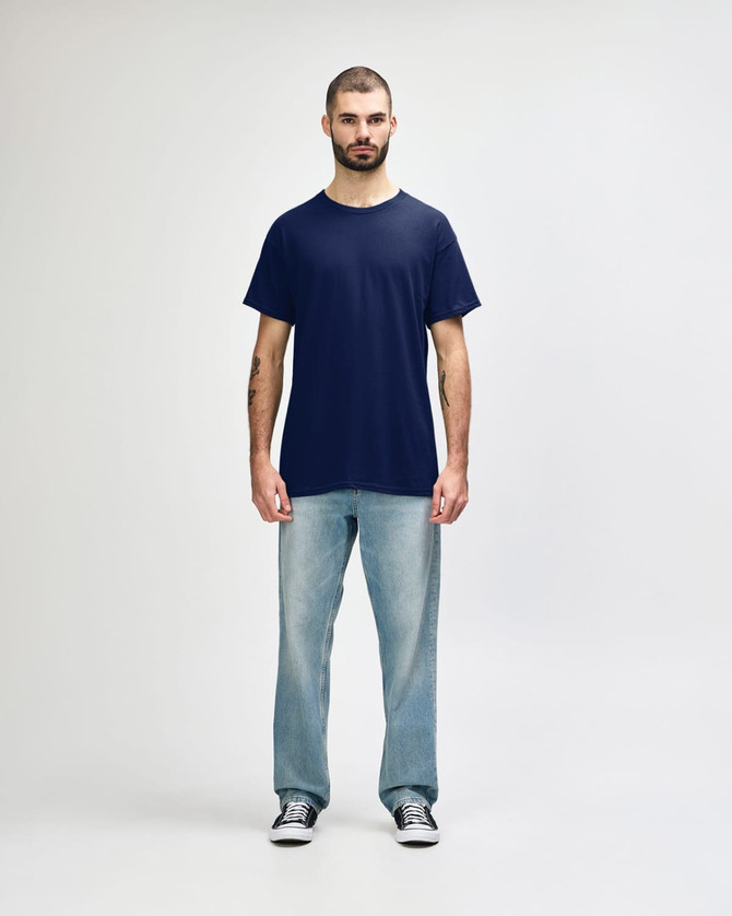 A navy Gildan Heavy Cotton adult T-shirt displayed on a model wearing black jeans and sneakers, with a logo present.