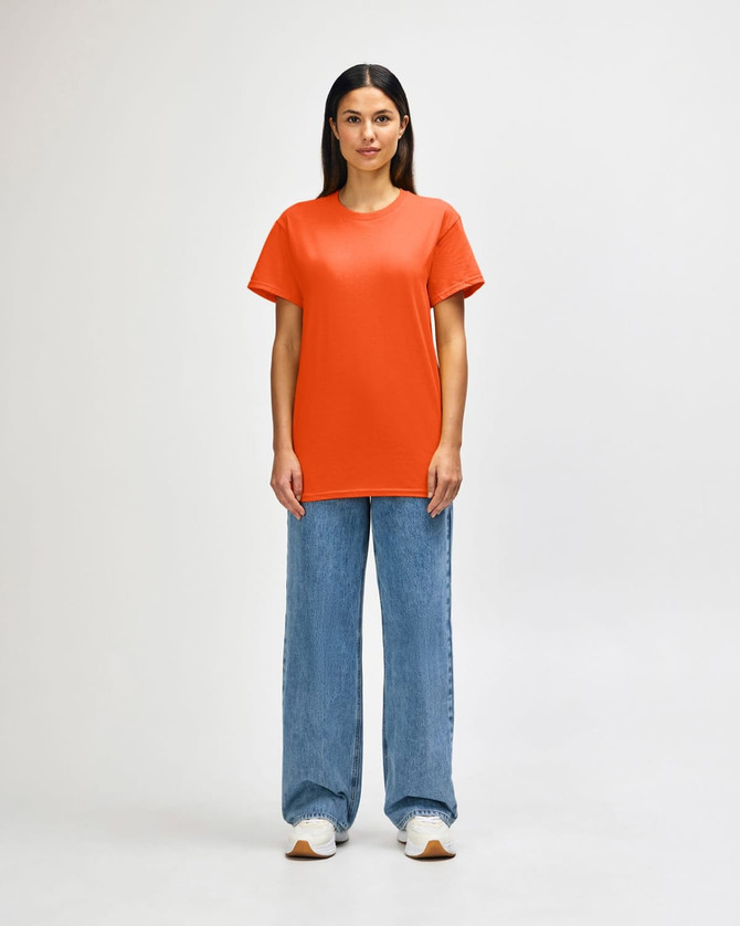 An orange Gildan Heavy Cotton Adult T-Shirt displayed on a male model, paired with black jeans and shoes.
