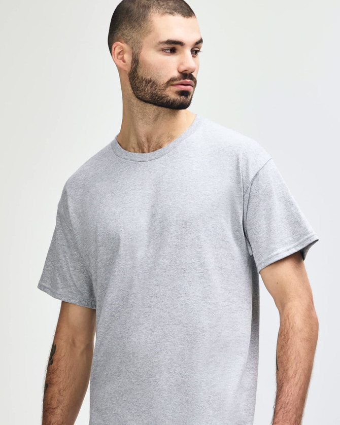 A grey Gildan Heavy Cotton Adult T-Shirt displayed on a model, featuring a simple design and a logo.
