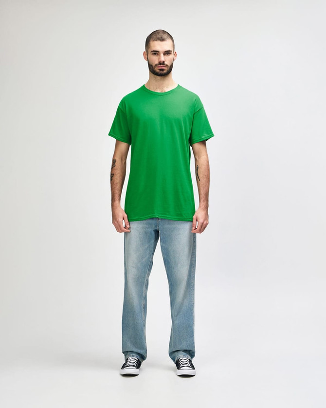 A green Gildan Heavy Cotton adult t-shirt displayed on a mannequin styled with black jeans and sneakers.