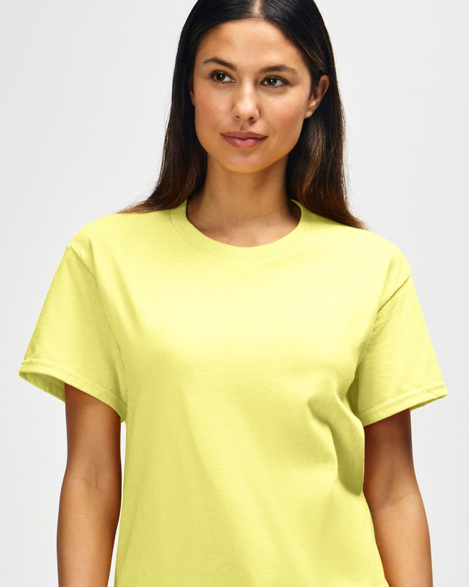 A close-up of a man wearing a bright yellow Gildan Heavy Cotton Adult T-Shirt. The shirt has a logo on it.