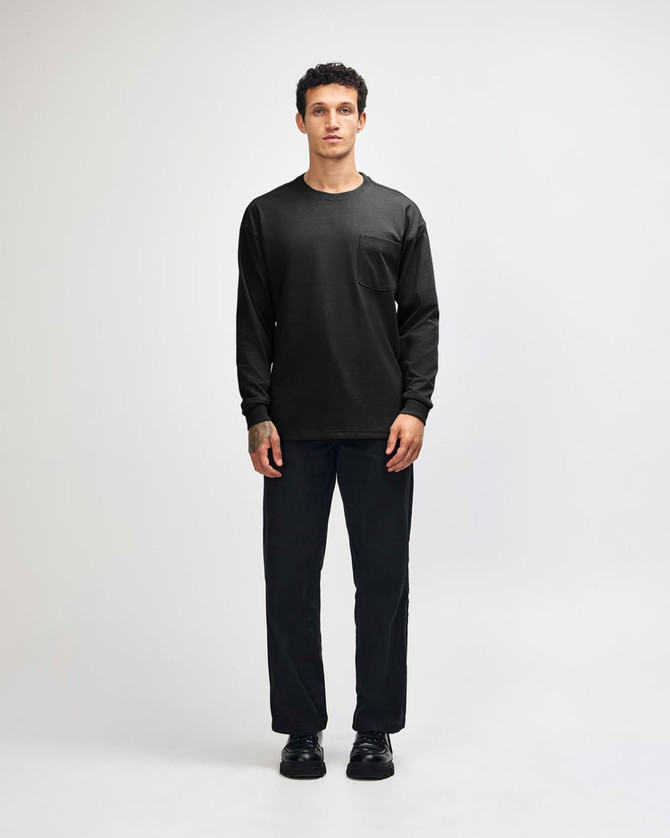 A black Super Heavyweight T-Shirt paired with loose blue jeans and black sneakers, displayed on a model.