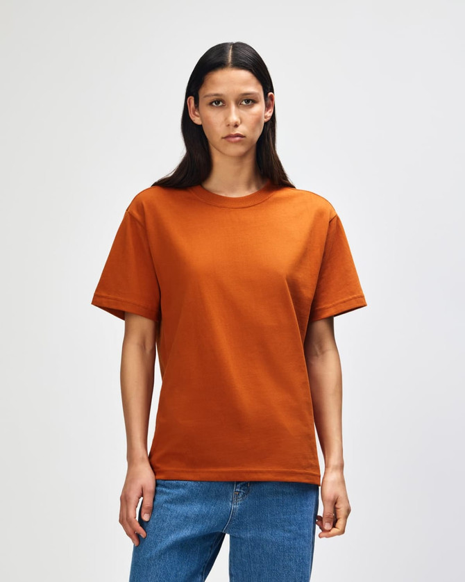 A man wearing an orange American Apparel Super Heavyweight T-Shirt, standing against a plain background.