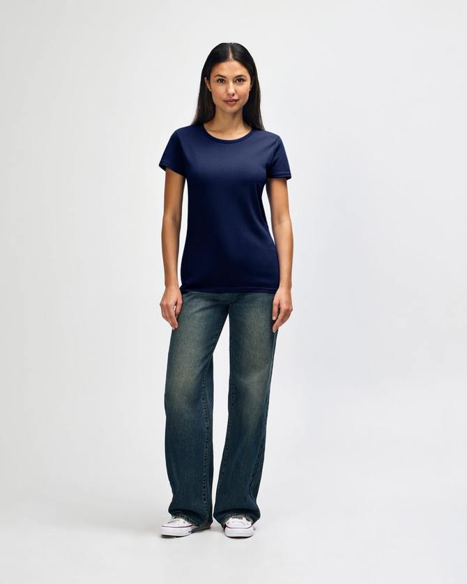 A model wearing a navy blue Gildan Heavy Cotton Ladies' T-Shirt paired with blue jeans and white sneakers.