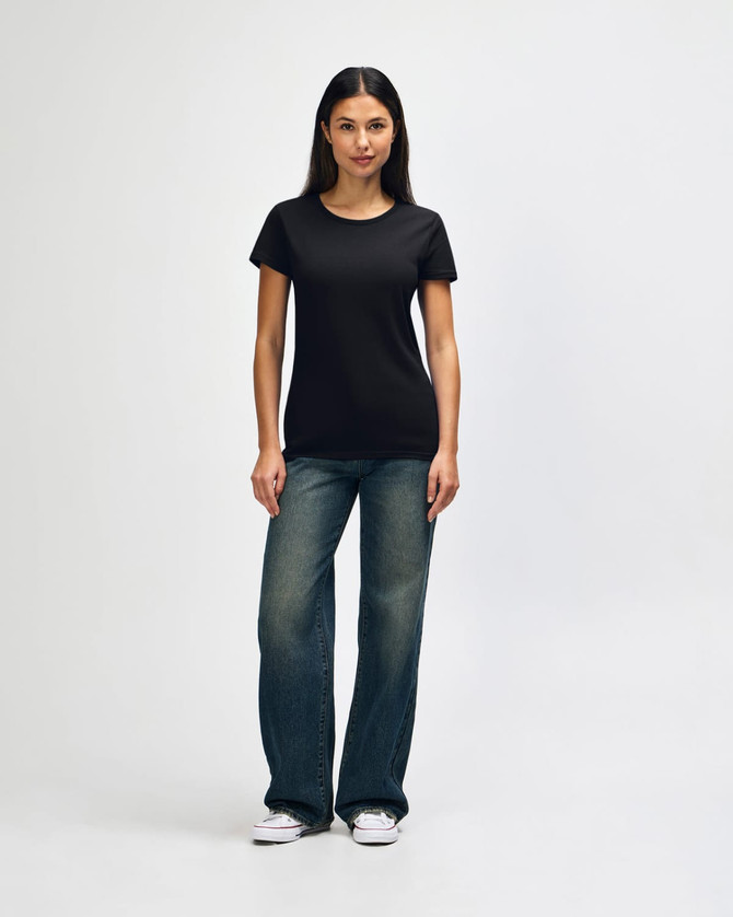 A black ladies' t-shirt displayed on a model, paired with blue jeans and white shoes, featuring a logo.