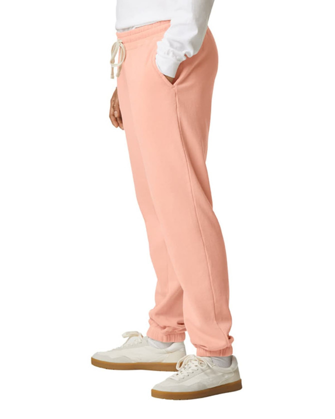 Lightweight peach sweatpants with pockets, featuring an elastic waistband and cuffs, alongside a logo.