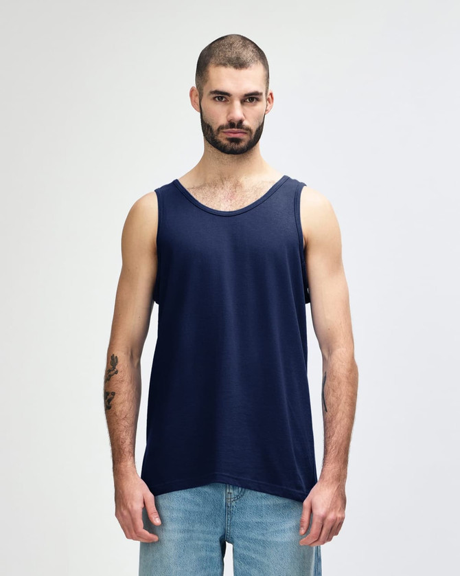 A navy Gildan Heavy Cotton adult tank top on a model standing against a plain background. The tank top has a logo.