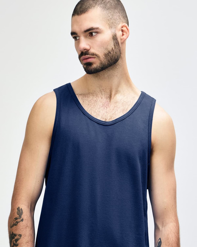 A navy blue Gildan Heavy Cotton adult tank top on a model, featuring a logo.