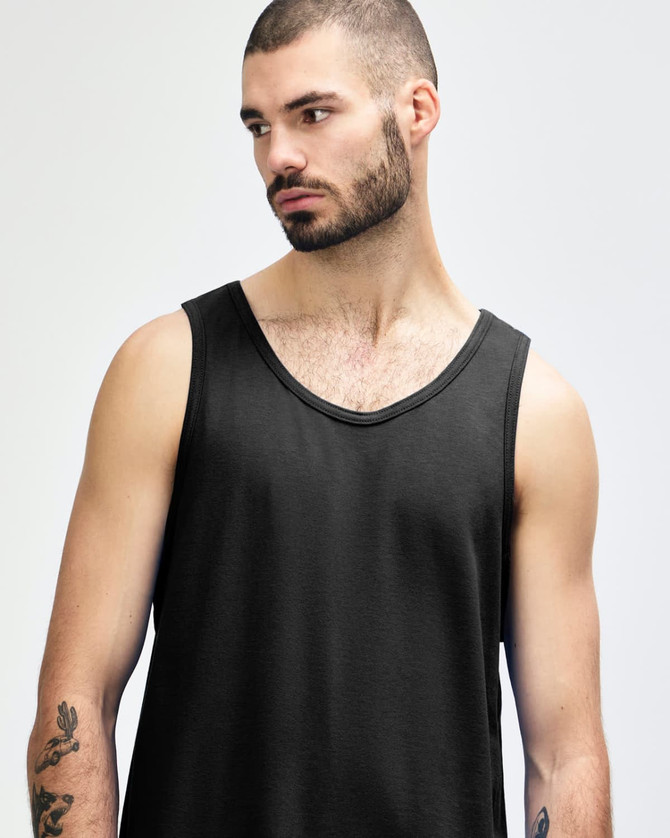 A black Gildan Heavy Cotton adult tank top displayed on a model. The tank features a round neckline and a relaxed fit.