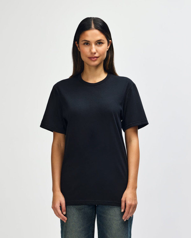 A model wearing a black Gildan Softstyle adult t-shirt paired with light blue jeans. The shirt has a logo.