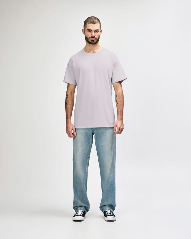 A light grey Gildan Softstyle adult t-shirt worn with blue jeans, featuring a logo on the t-shirt.