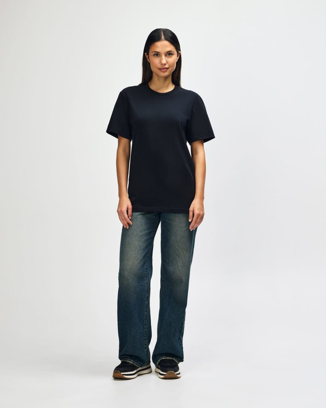 A black Gildan Softstyle adult T-shirt displayed on a model wearing light blue jeans and white shoes, with a plain background.